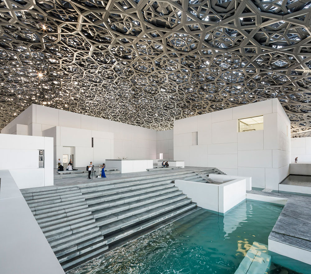 Light from the canopy above reflects into the pools of water to create a mesmerizing effect. The Louvre,Abu Dhabi. © Photography by Luc Boegly & Sergio Grazia. Architecture by Jean Nouvel. Engineering by BuroHappold. Steel construction by Waagner Biro.